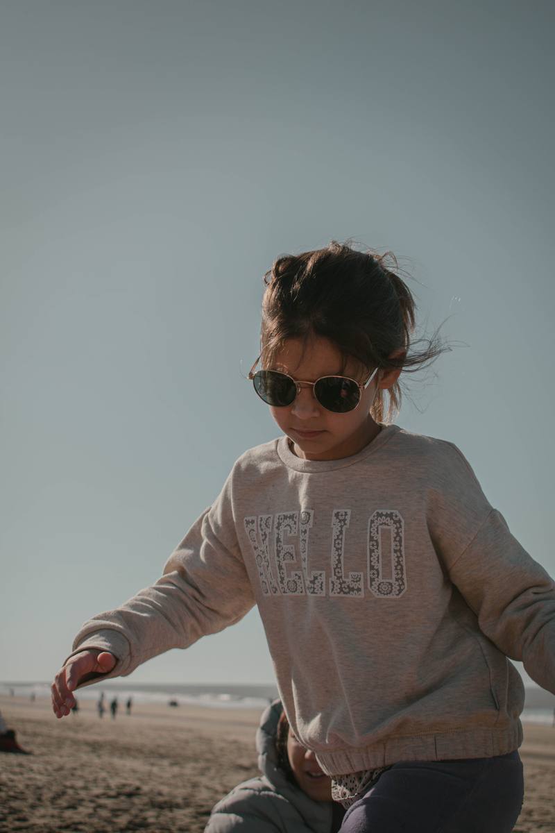 Nena caminando por la playa a contraluz