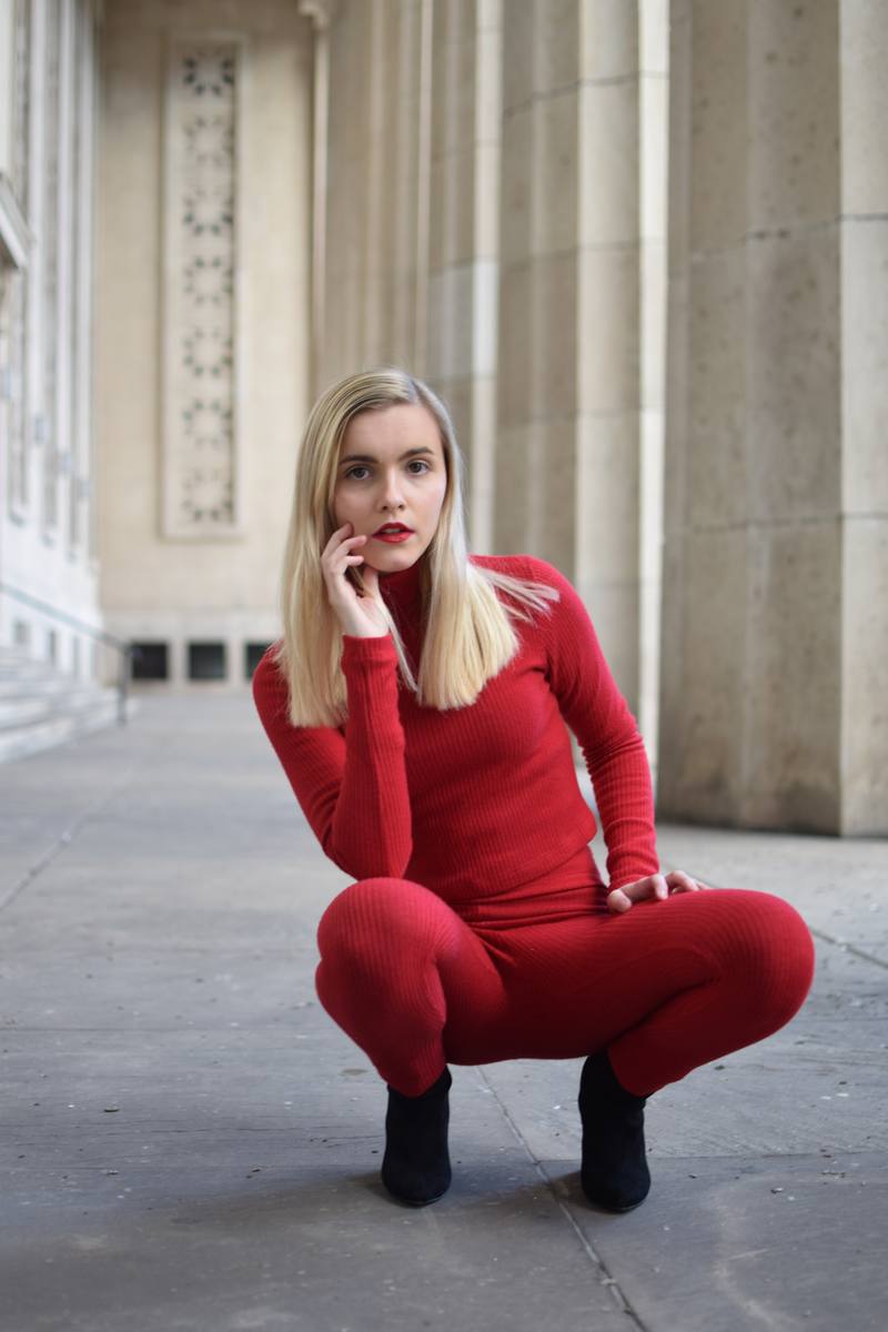 Retrato de mujer con conjunto rojo entre columnas